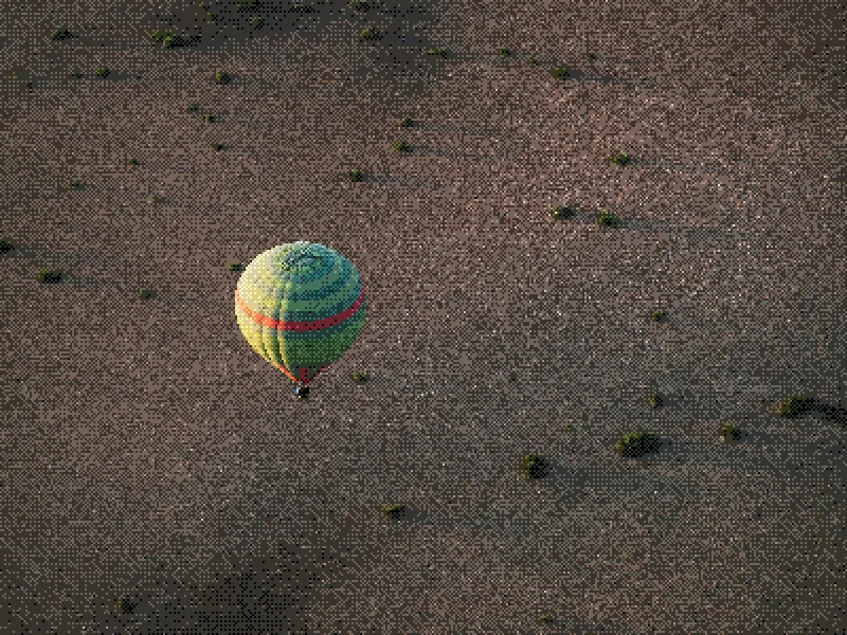 Aerial view of a colorful hot air balloon floating over an arid landscape